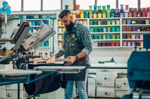 Male worker using printing machine in a workshop